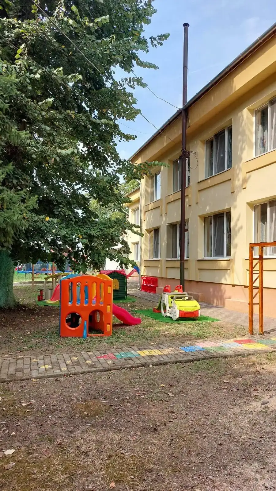 Clădirea grădiniței și spațiul de joacă amenajat din curte